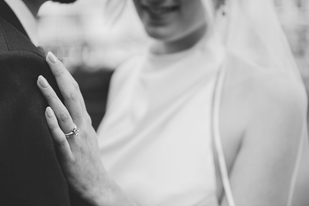 Close-up black and white photo showing a hand wearing an elegant engagement ring.