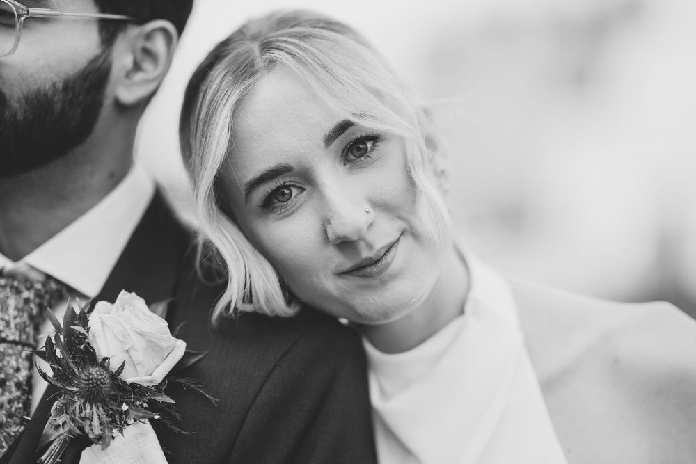 Black and white portrait of a couple on their wedding day with a floral boutonniere.