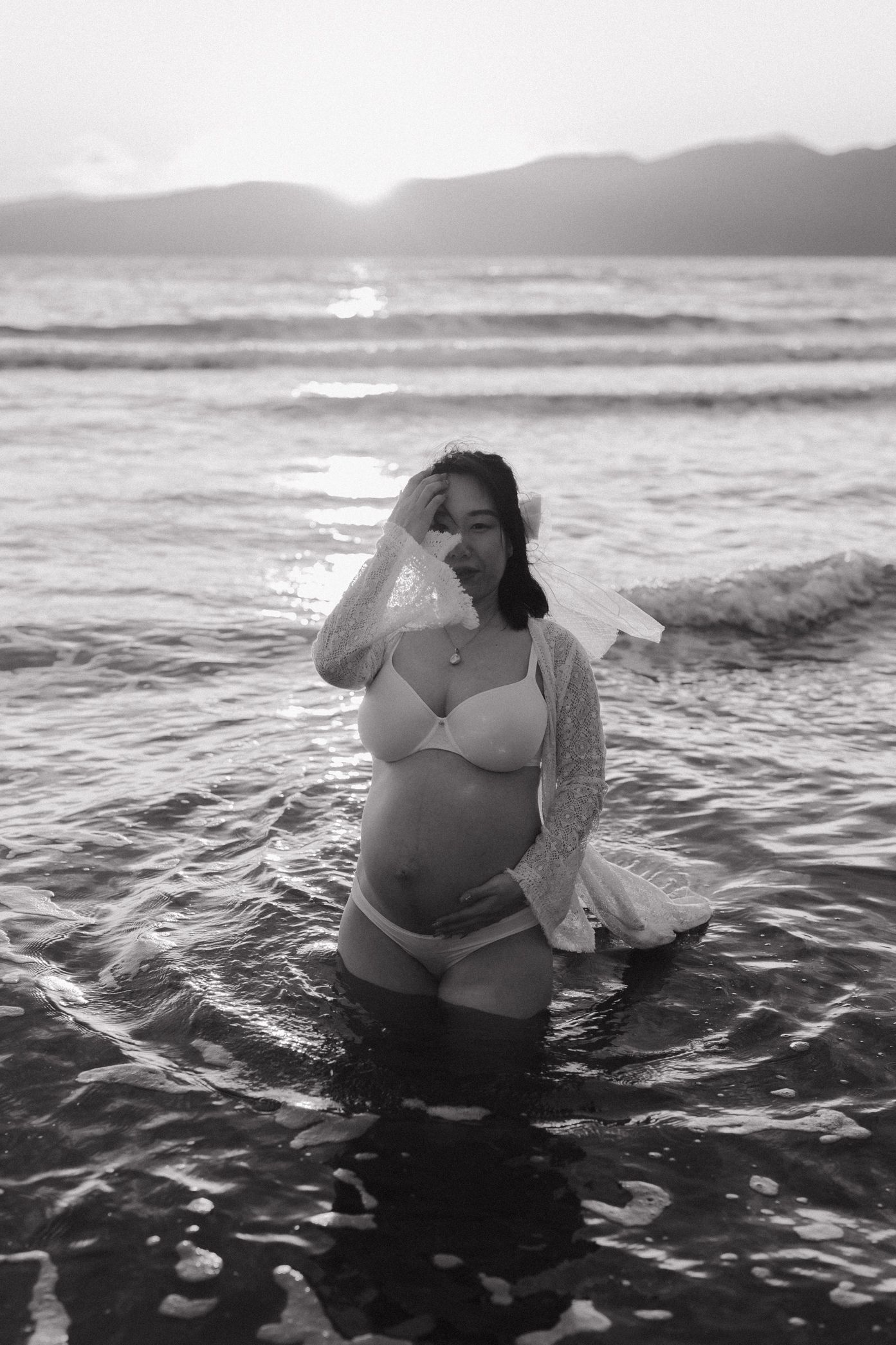 A series of black and white photographs showing a couple embracing in ocean waves at sunset.