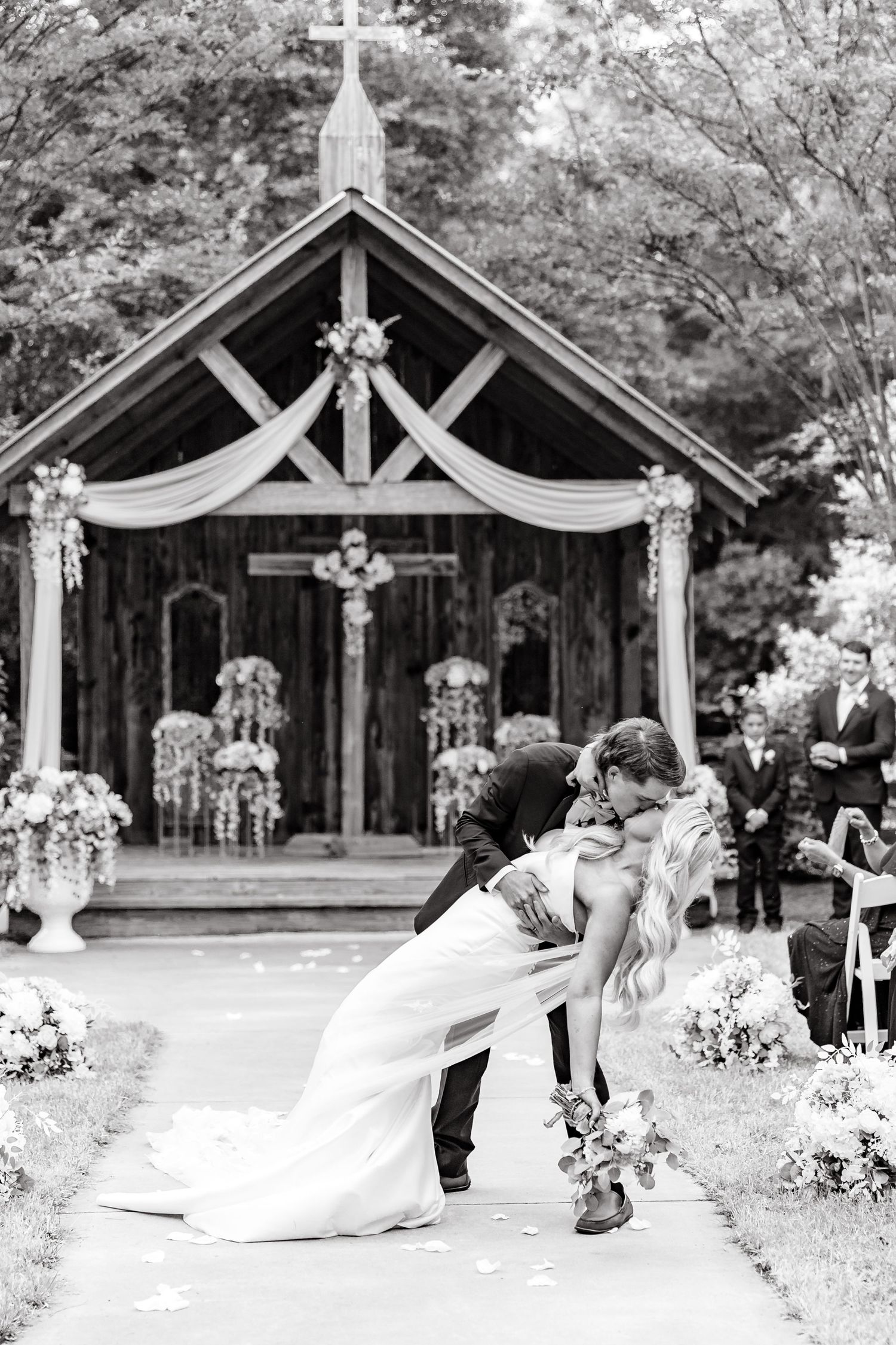 A black and white wedding photo sequence showing a couple dancing under rustic wooden pavilions decorated with flowers.
