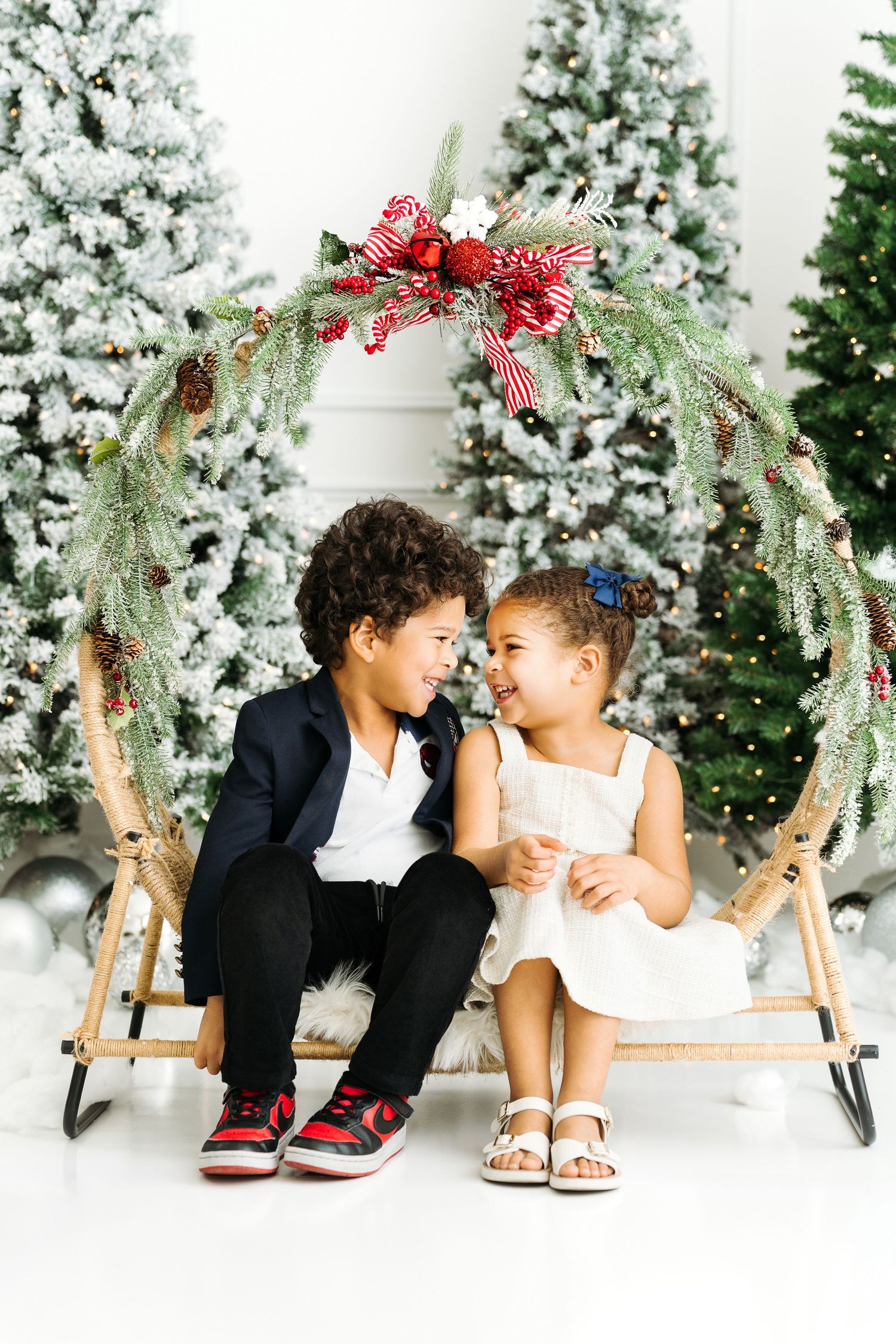 Child sitting inside large Christmas wreath in holiday photoshoot