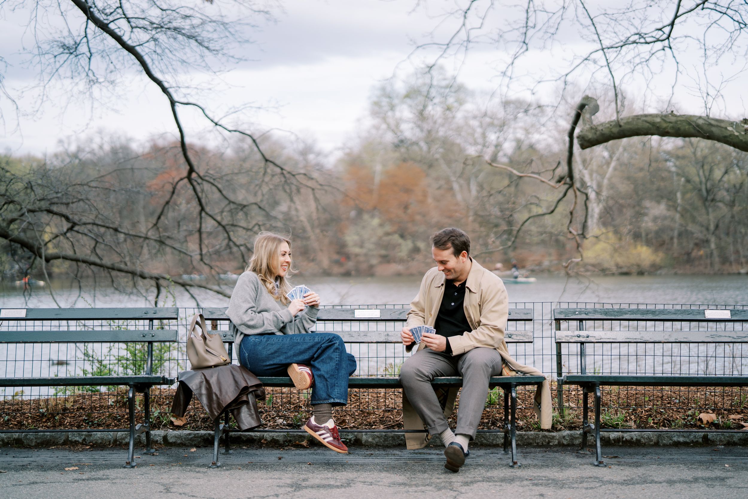 A couple lounges and relaxes together on a wooden bench in a serene park setting during autumn.