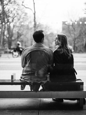 A couple sits together on a park bench in a black and white photograph showing four progressive stages of closeness.