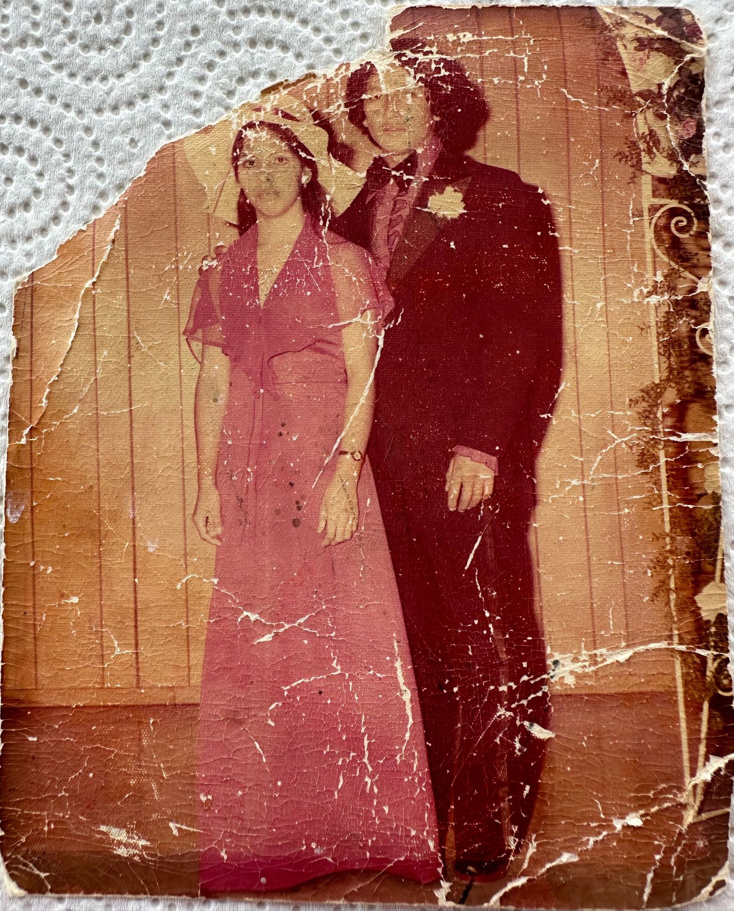 A damaged vintage sepia photograph from the early 1900s shows a formal gathering in front of a wooden wall.