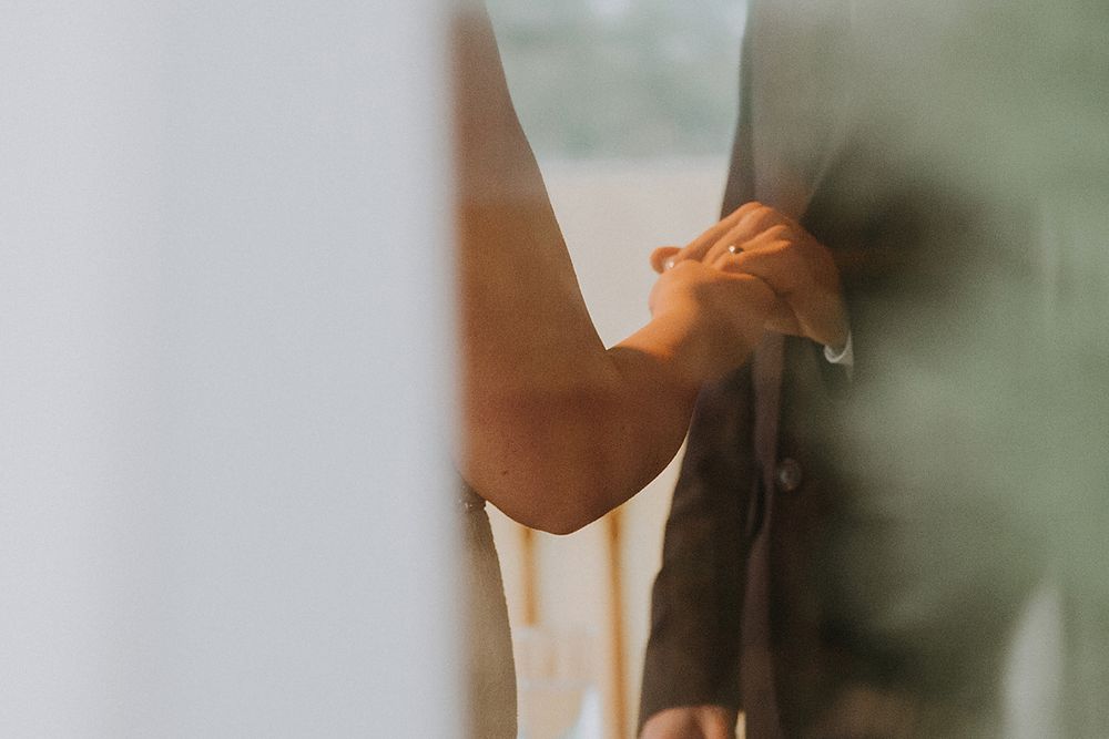 A person's hand reaches upward against a soft blurred green background in warm natural lighting.