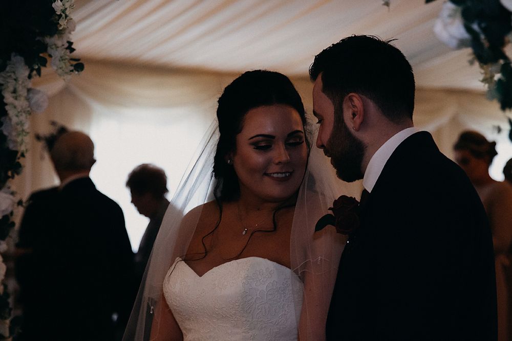 A couple shares an intimate dance moment at their wedding reception under soft lighting.
