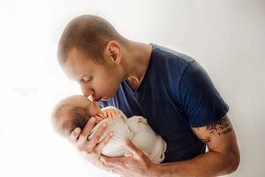 Father cradling newborn in bright light – Springfield Missouri newborn photographer.
