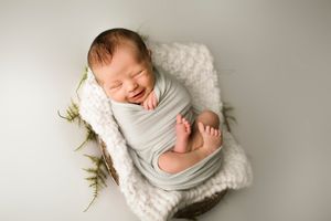 Laughing newborn boy wrapped in blue blanket - Springfield Missouri Newborn Photographer.