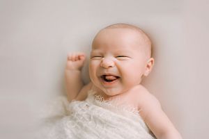 Laughing newborn boy on white blanket - Springfield, MO Newborn Photographer.