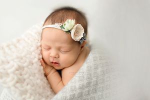 Newborn photo on white blanket with floral headband - Springfield Missouri Newborn Photographer.