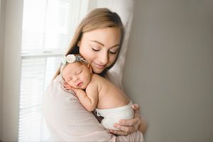 Mother holding newborn baby in soft natural light – Amber Potter Photography.