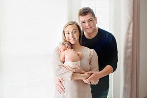 Family cuddling newborn in light neutral studio – Springfield Missouri.
