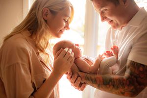 Parents smiling over newborn wrapped in cream tones – Amber Potter Photography Springfield.