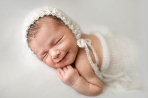 Natural light newborn photo of baby in bonnet in cream tones - Springfield Missouri Newborn Photographer.