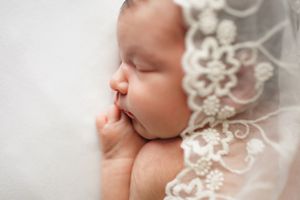 Newborn baby in lace laying on neutral blanket on white background – Springfield MO.