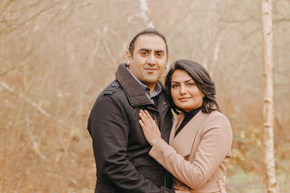 A couple shares an intimate moment during their outdoor engagement photo session in a rustic fall setting.
