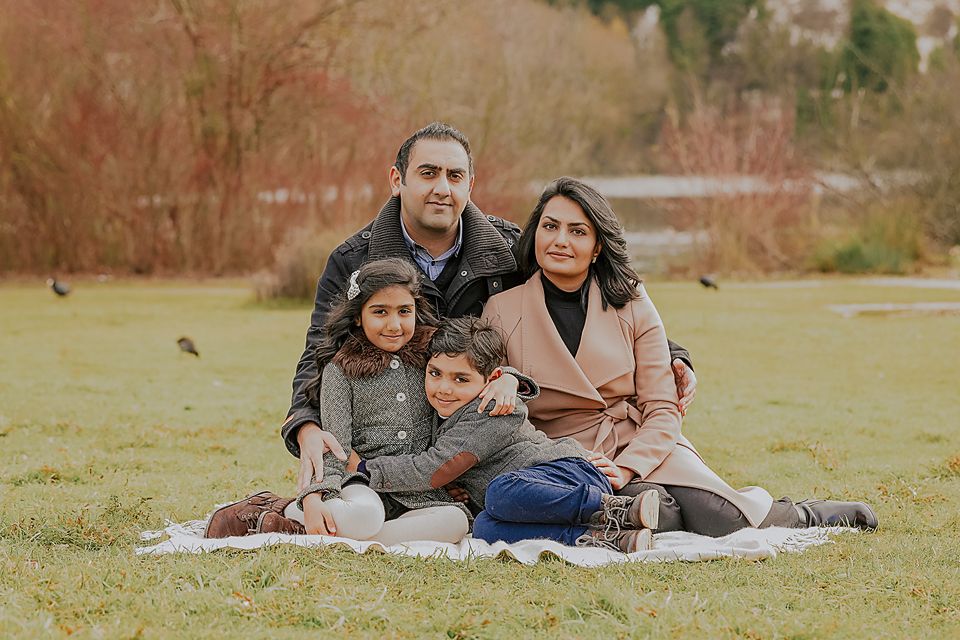 A family relaxes together on a blanket in a grassy field during an outdoor photo session.