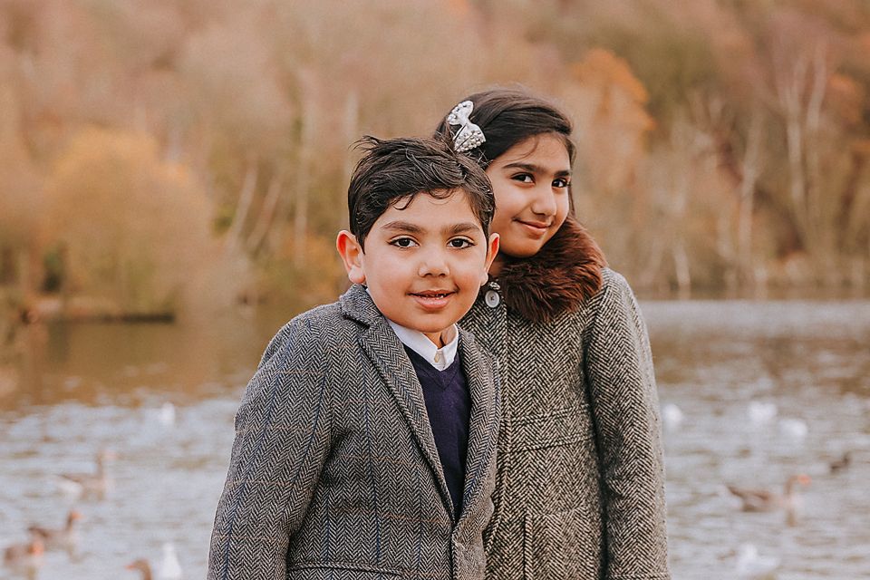 Couple sharing a tender moment while seated on a wooden bench near a serene lake.