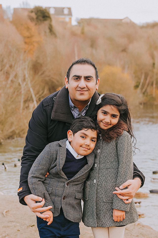 Candid outdoor portraits of a family embracing and laughing together near a pond.