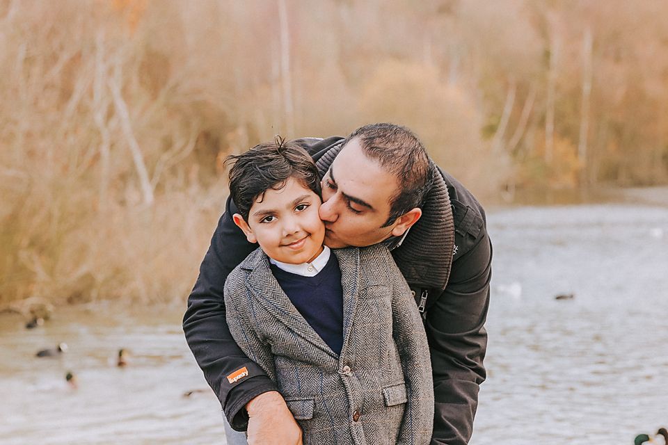 Sweet family moments captured in a series of affectionate poses by a lake during autumn.