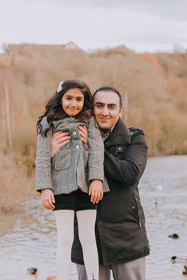 A parent and child share a tender moment outdoors on a winter day, both wearing warm coats.