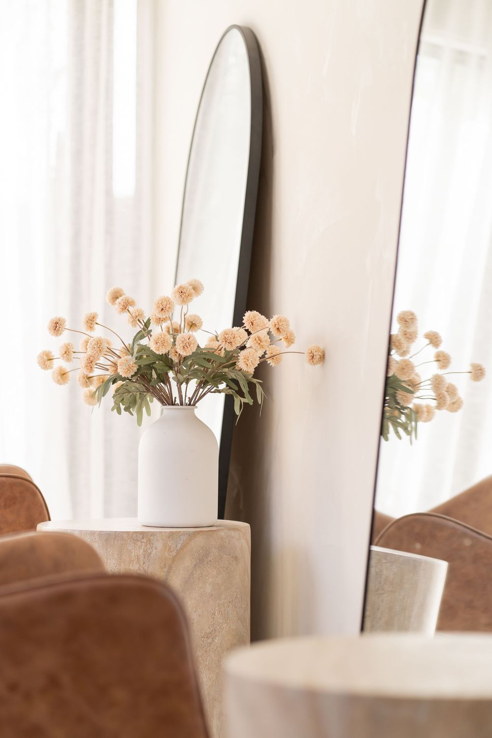 Elegant dining room interior with beige chairs and delicate peach floral arrangements on a table.