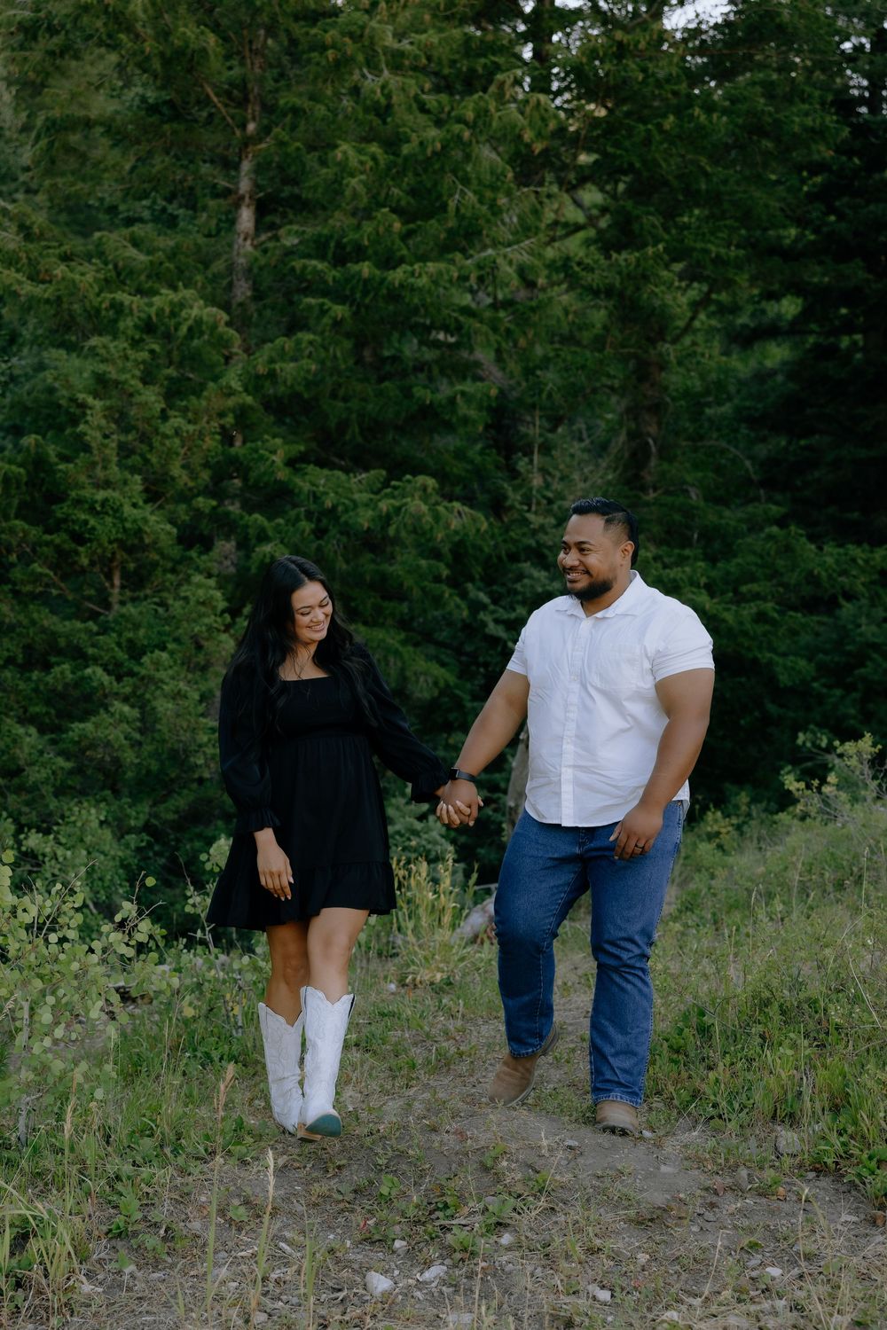 A couple poses together in a natural outdoor setting with trees and grass in the background.