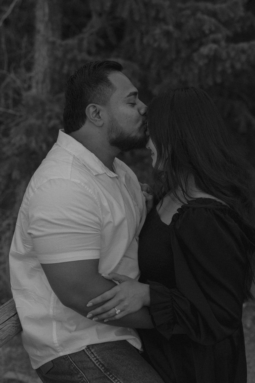 Intimate black and white portrait of a couple sharing romantic moments outdoors.
