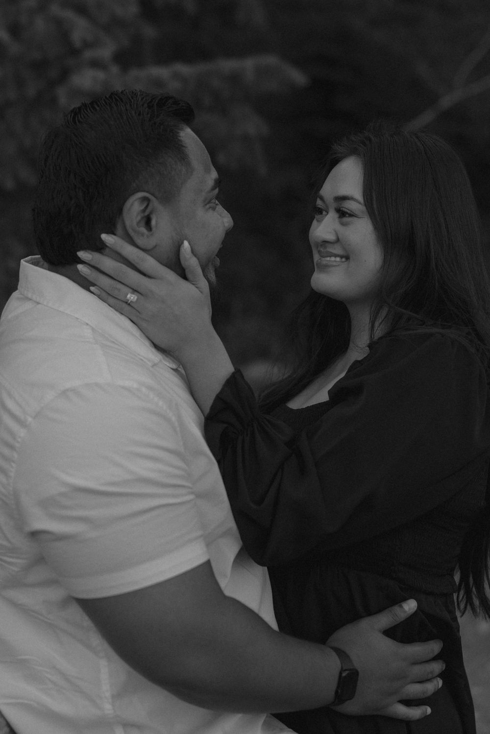 Couple sharing tender moments and embraces in a moody black and white outdoor setting.