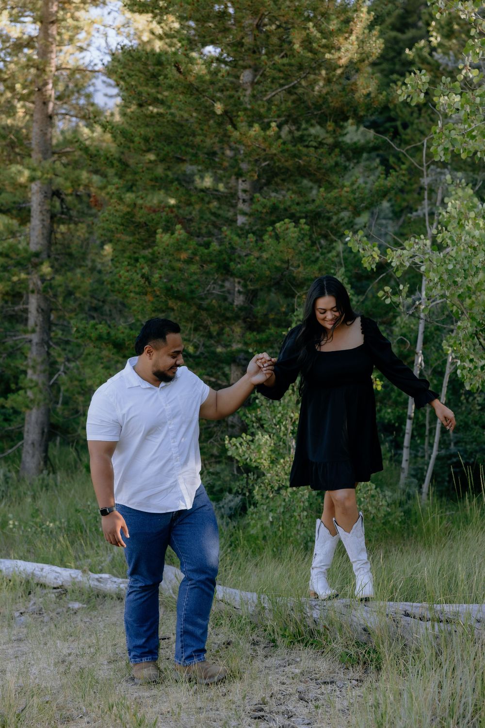 A couple dances together on a mountain trail surrounded by green foliage.