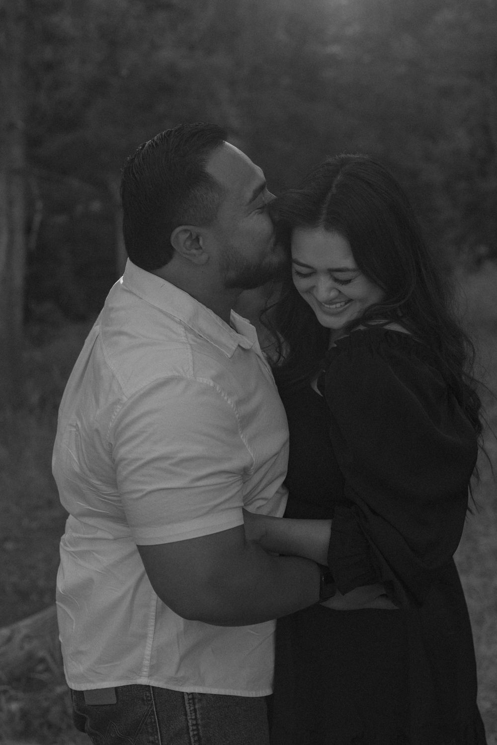 A romantic black and white photo captures an intimate moment between two people in an outdoor setting.