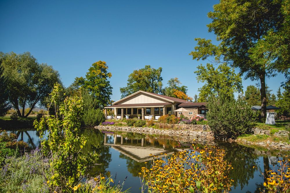 Scenic lakeside property with lush gardens and multiple residential buildings along the waterfront on a sunny day.