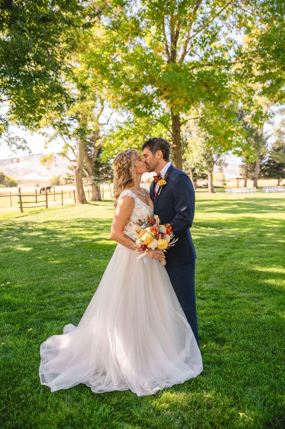 A romantic outdoor wedding photoshoot on a lush green lawn with trees in the background on a sunny day.