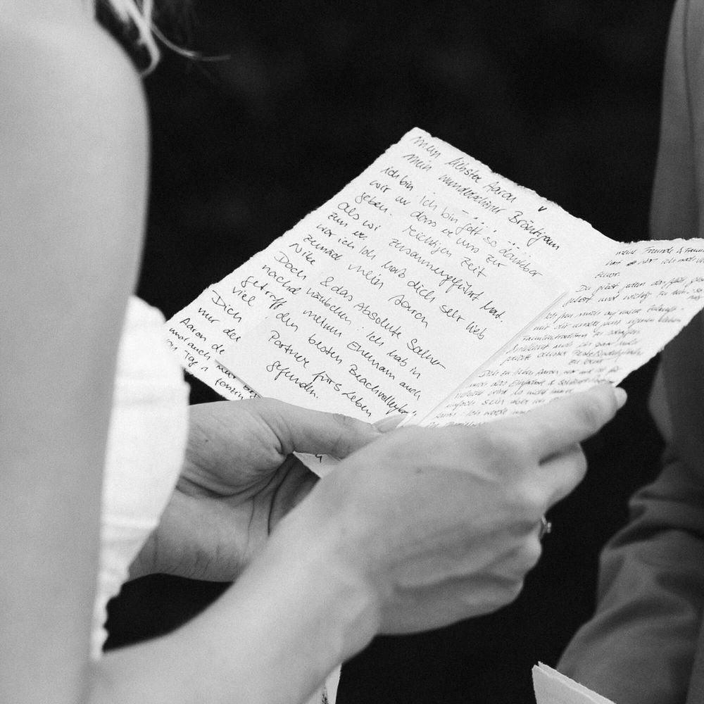 Close-up view of hands holding handwritten letters or notes in black and white.