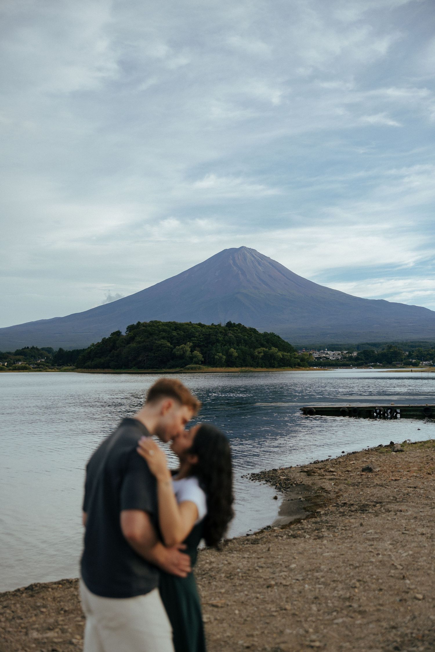 Mount Fuji rises majestically above Lake Kawaguchiko on a cloudy day in Japan during couple engagement photoshoot