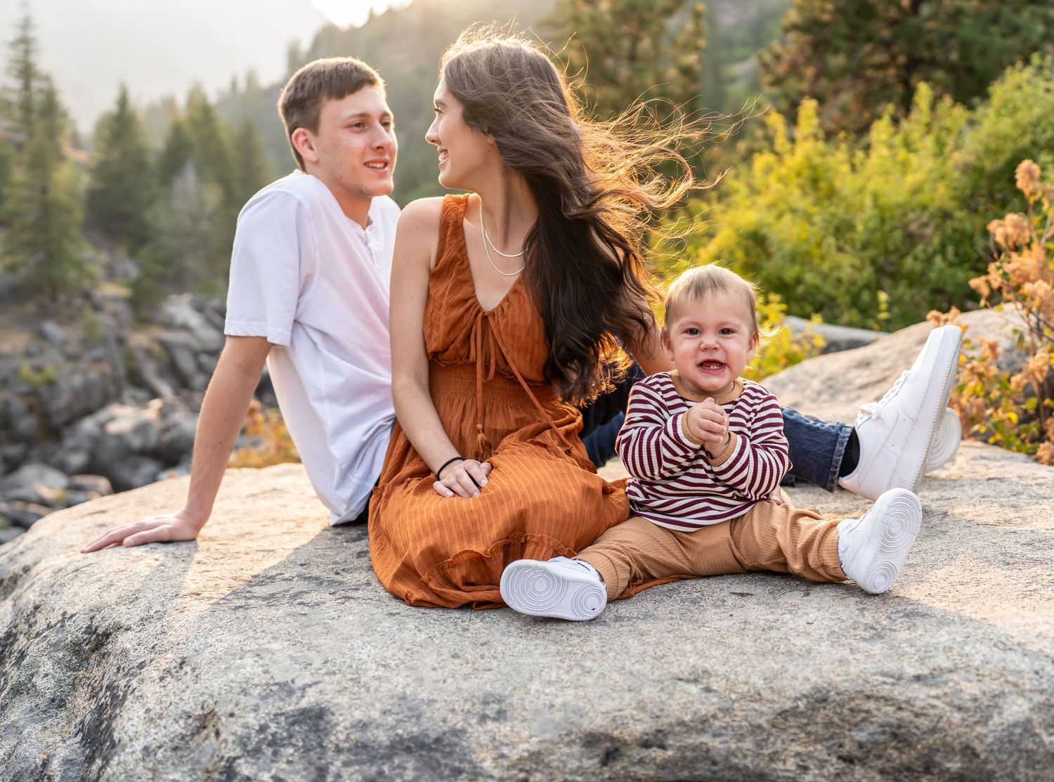 Family enjoying a tender moment while sitting on a rocky mountain overlook.