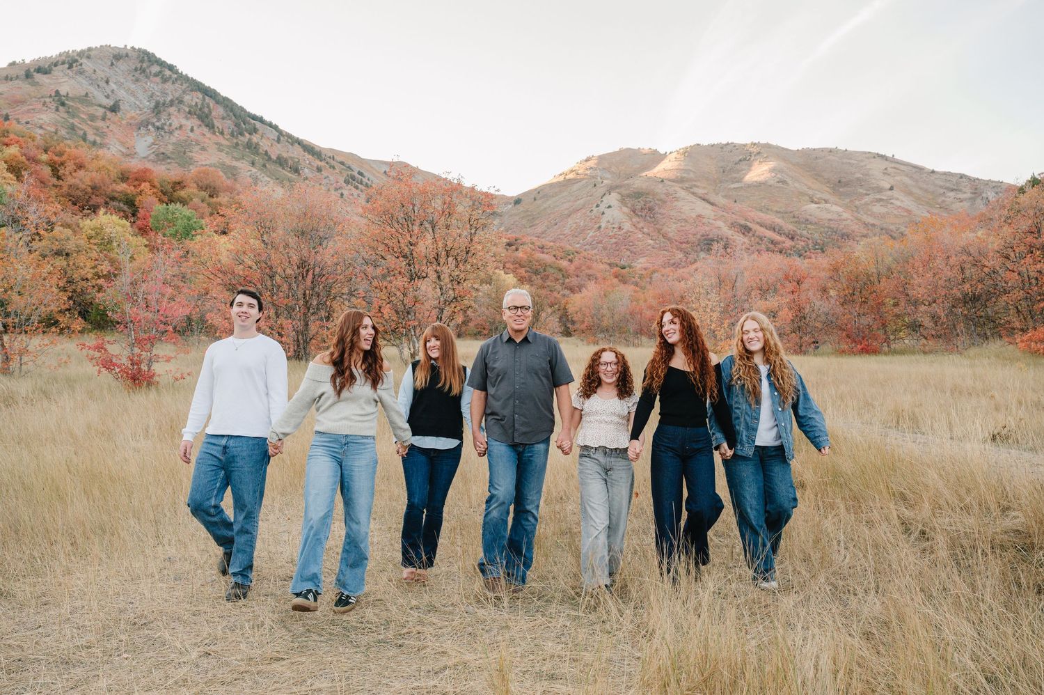 Group walking together in autumn field with mountains and fall foliage in the background.