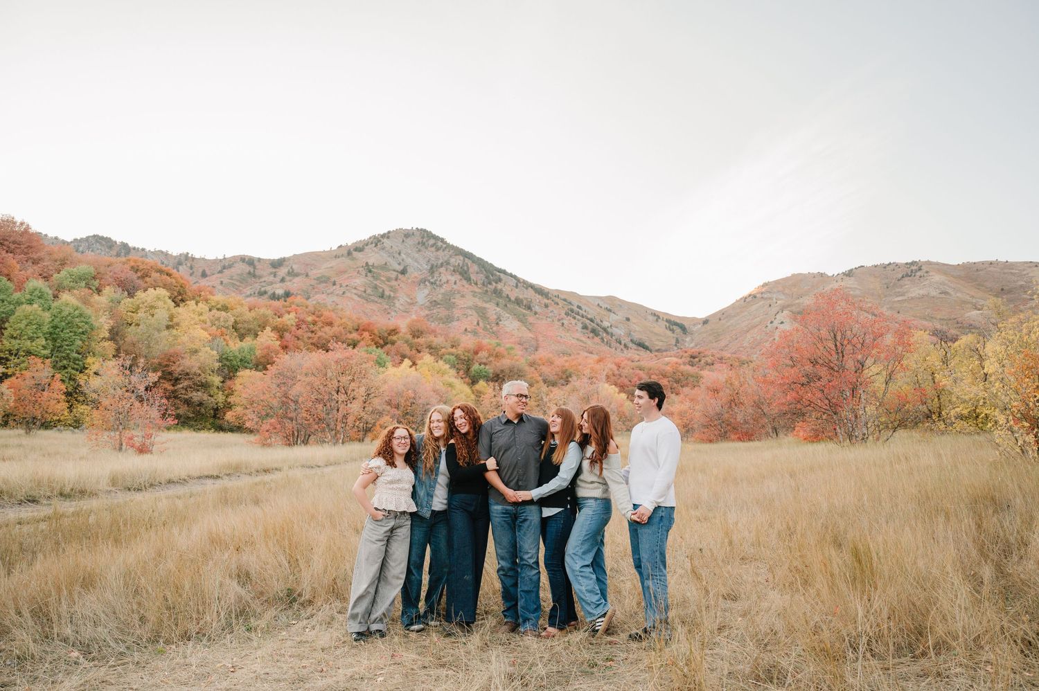 A series of landscape photos showing mountain views and group gatherings in a golden grassy field during autumn.