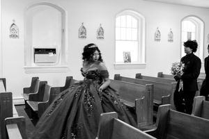 Interior church scene with wooden pews and religious statues along white walls.