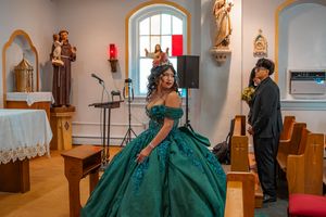 Person wearing a sparkly emerald green ballgown poses inside a church with arched windows.