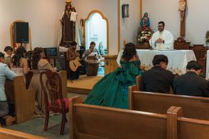 Church ceremony with musicians and attendees watching someone in an emerald green gown.