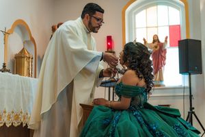 Church service with clergy in white robes and person in emerald formal dress.