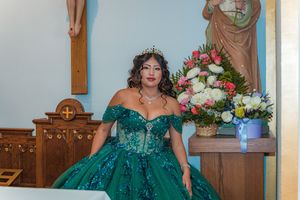 Stunning emerald quinceañera dress with off-shoulder design and ornate details in church setting.