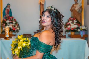 Portrait with yellow bouquet and emerald gown against religious altar backdrop.