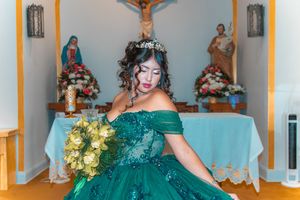 Emerald green formal dress with off-shoulder design photographed in church setting.