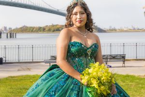 Stunning emerald green ball gown with sequin details photographed against a waterfront backdrop.