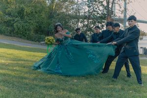 Wedding party playfully poses on grassy lawn in formal attire.