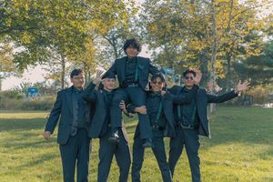 Group in formal wear creates fun poses outdoors on sunny day.