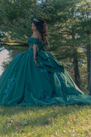 Flowing emerald green ballgown captured in natural outdoor setting.