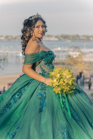 Emerald quinceañera dress with yellow bouquet photographed by waterfront.